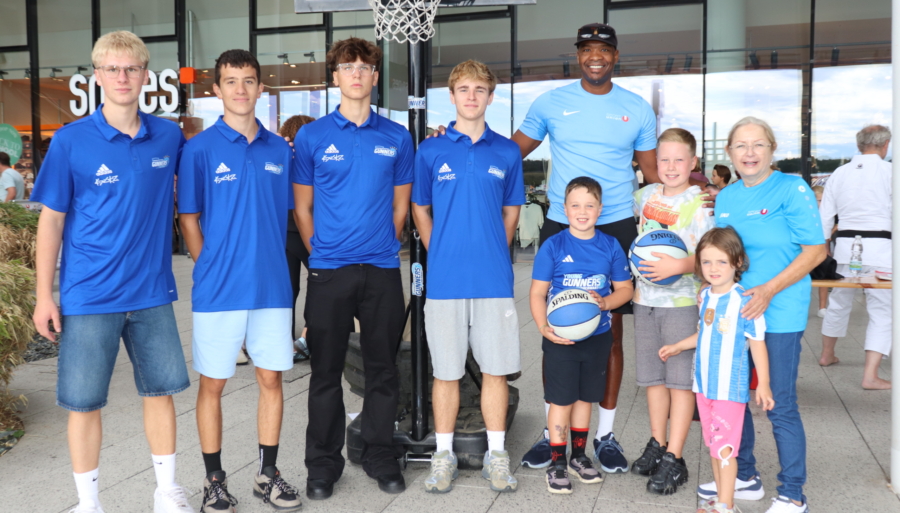 Basketball-Team mit Trainern und Kindern posiert vor einem Basketballkorb