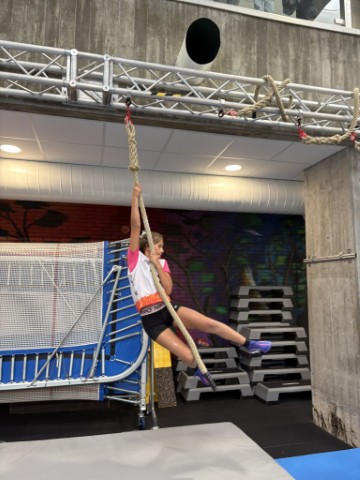 Mädchen klettert an einem Seil im Indoor-Spielplatz in Österreich.