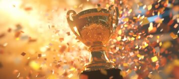 Golden trophy cup with confetti on golden background.