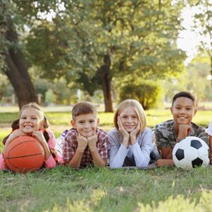 Cute kids with sport balls on green grass