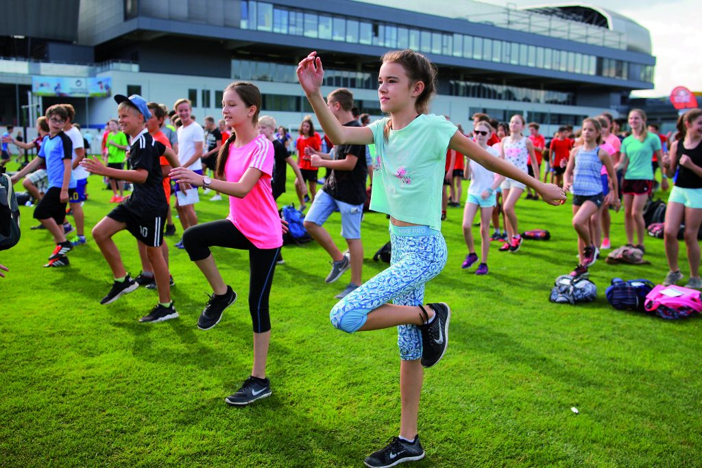 Tanzende Kindergruppe auf Sportplatz